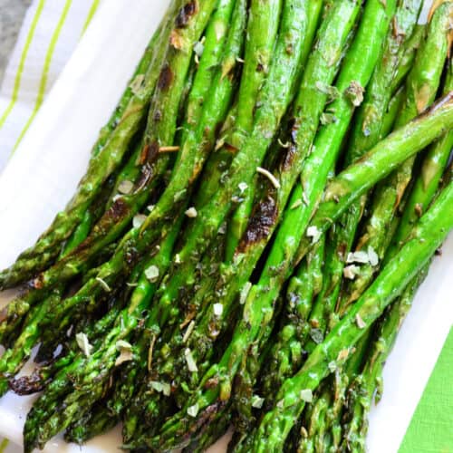 Top view of Grilled Italian Herb Asparagus on rectangle plate with pinterest title text.