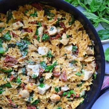 Top view of pan filled with bowtie pasta, sundried tomato, chicken, basil, and cheese.