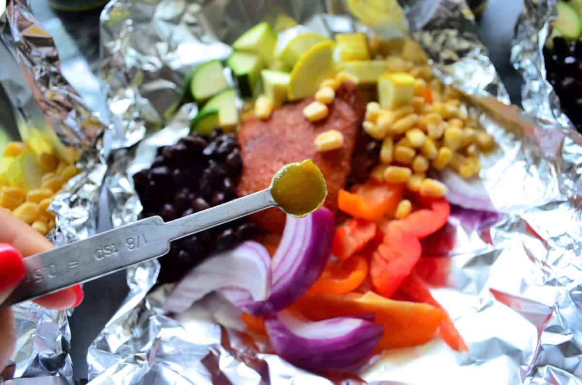 ⅛ teaspoon of yellow substance held over aluminum foil containing vegetables.