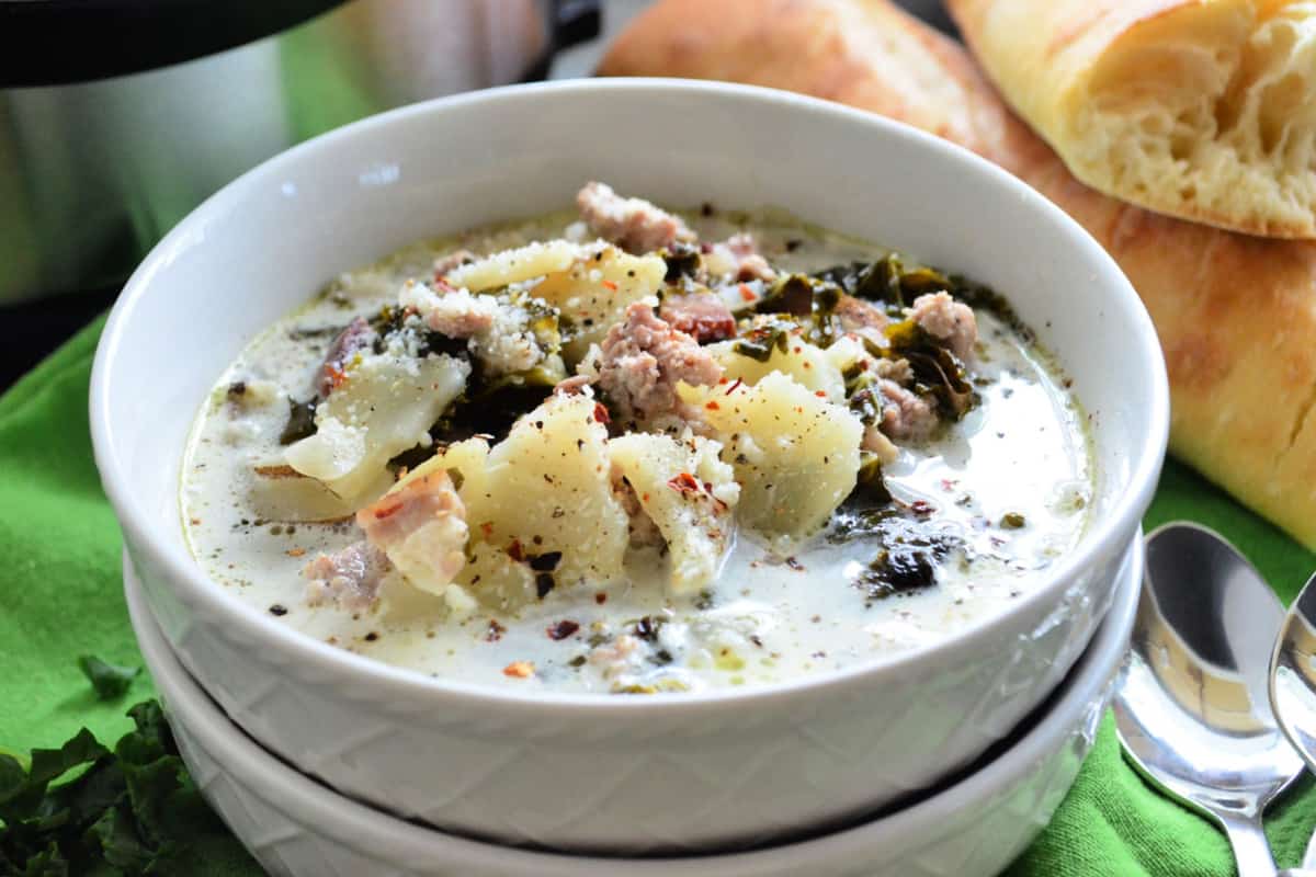 Close up Bowl of creamy soup with potatoes and herbs on top.