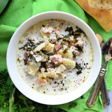 Top View Bowl of creamy soup with potatoes and herbs on top.