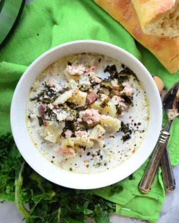 Top View Bowl of creamy soup with potatoes and herbs on top.