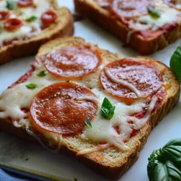 Close up of toast pepperoni pizza next to basil.