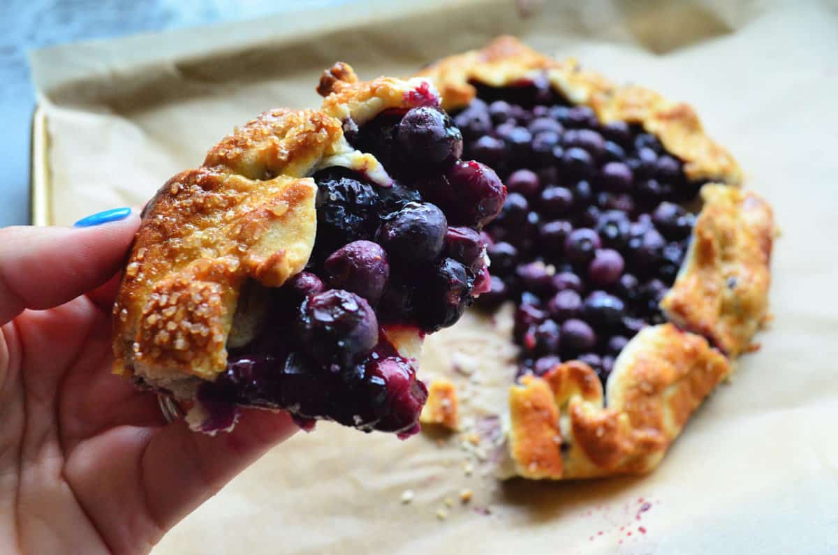 close up piece of blueberry crostata with bite missing and remaining crostata blurred in background.