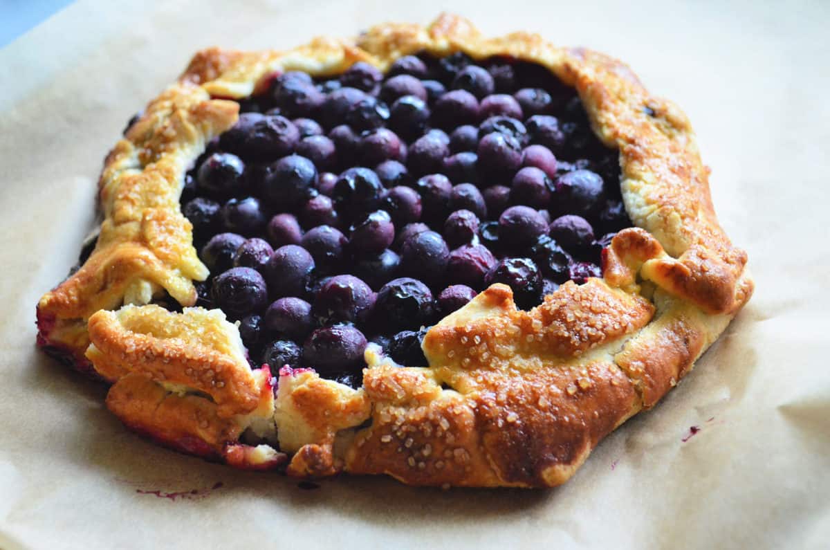 top view of flakey uneven pie crust with cooked blueberries as filling.