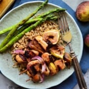 Grilled Chicken, red onion, and figs skewered over bed of rice served with asparagus on plate.