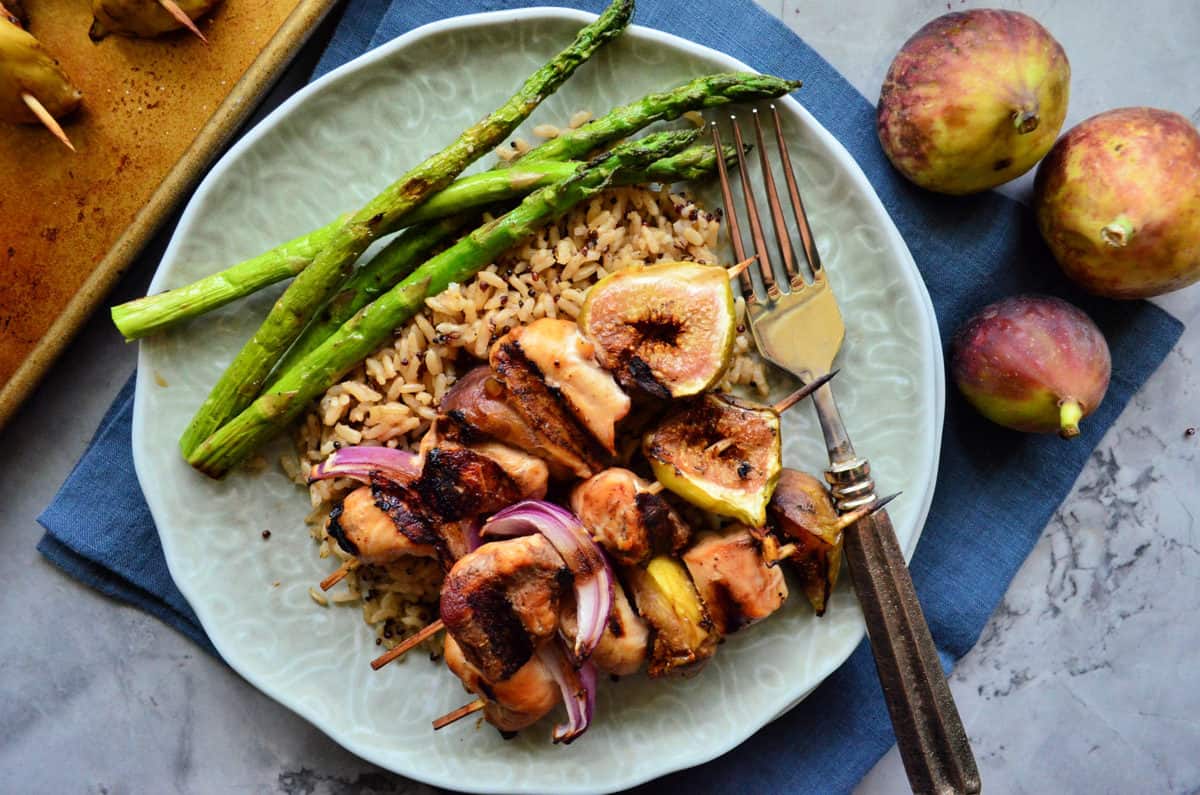 plated chicken skewers with onion, figs, rice, asparagus with for next to whole figs.