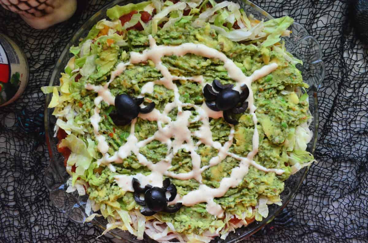 Guacamole Dip topped with Olives arranged to look like spiders and dressing to look like web.