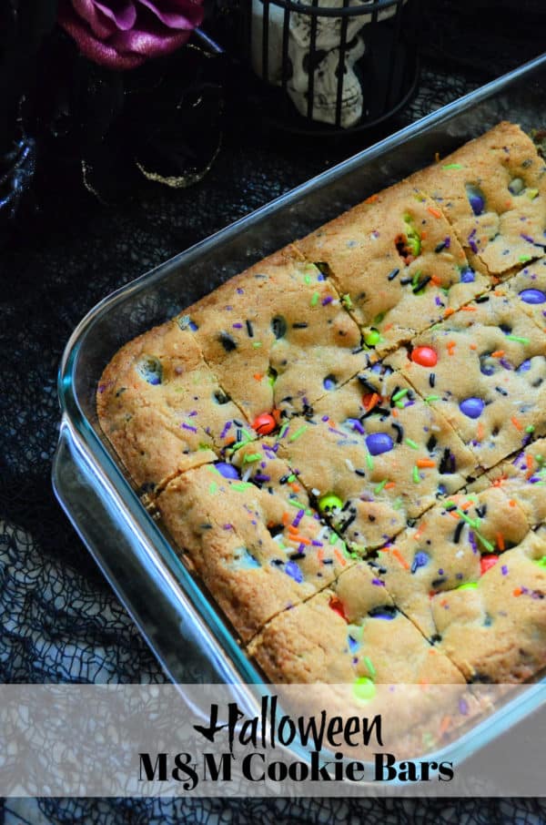 Halloween M&M Cookie Bars in glass baking dish with pinterest title text.