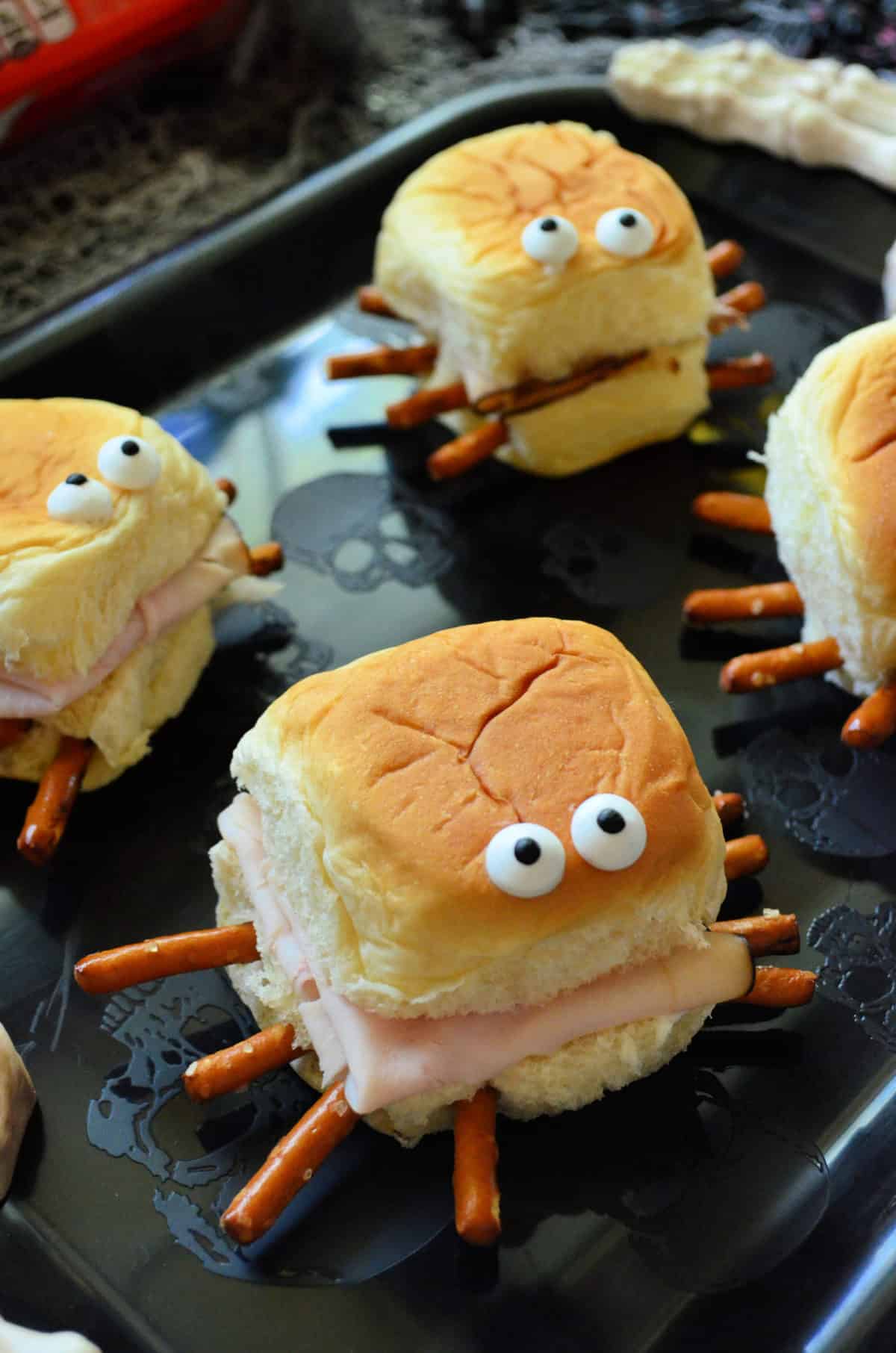 closeup of small rolls with turkey, pretzels sticking out like spider legs, and candy eyes on top. 