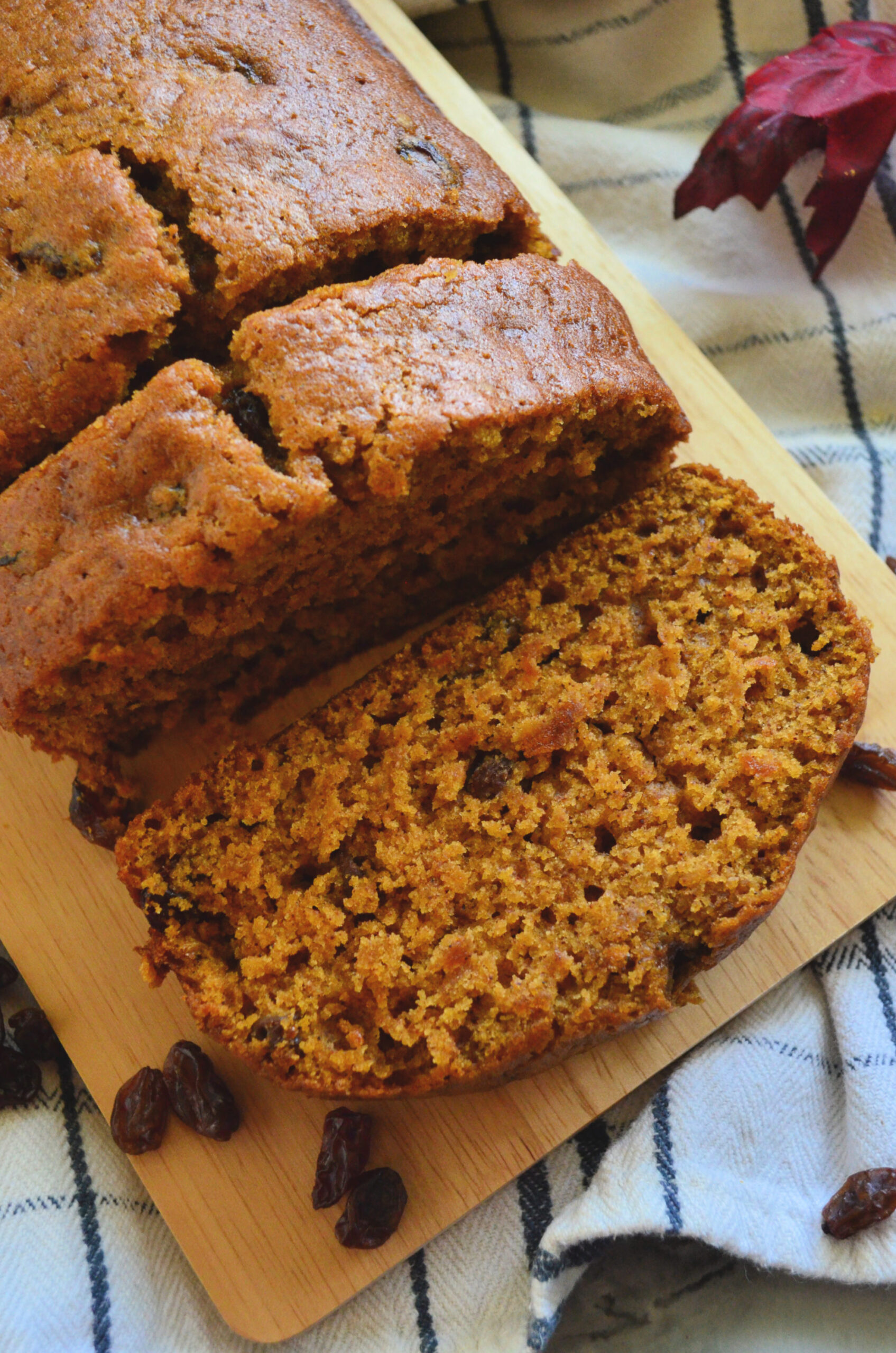 Top closeup view of pumpkin bread loaf on board with two slices cut and resting.