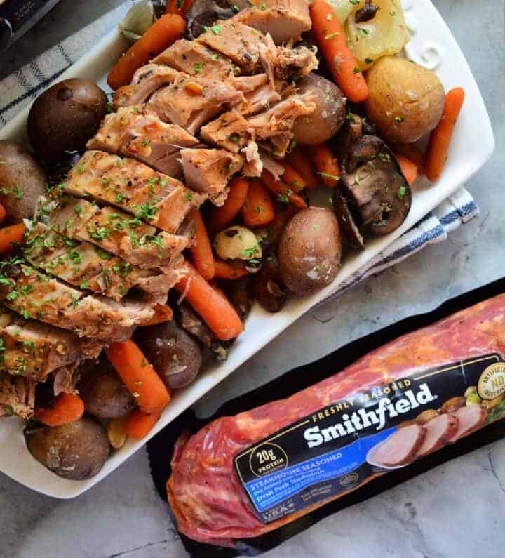 Plated Pork Tenderloin on bed of carrots and potatoes next to package of Smithfield.