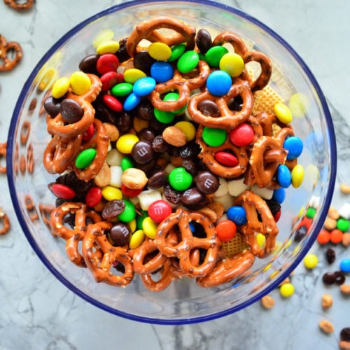 Top view of bowl of M&Ms, pretzels, popcorn, and peanuts.