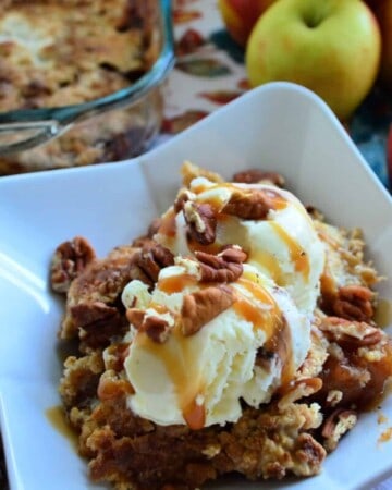 Close up of Bowl of cake topped with ice cream, pecans and drizzled caramel.