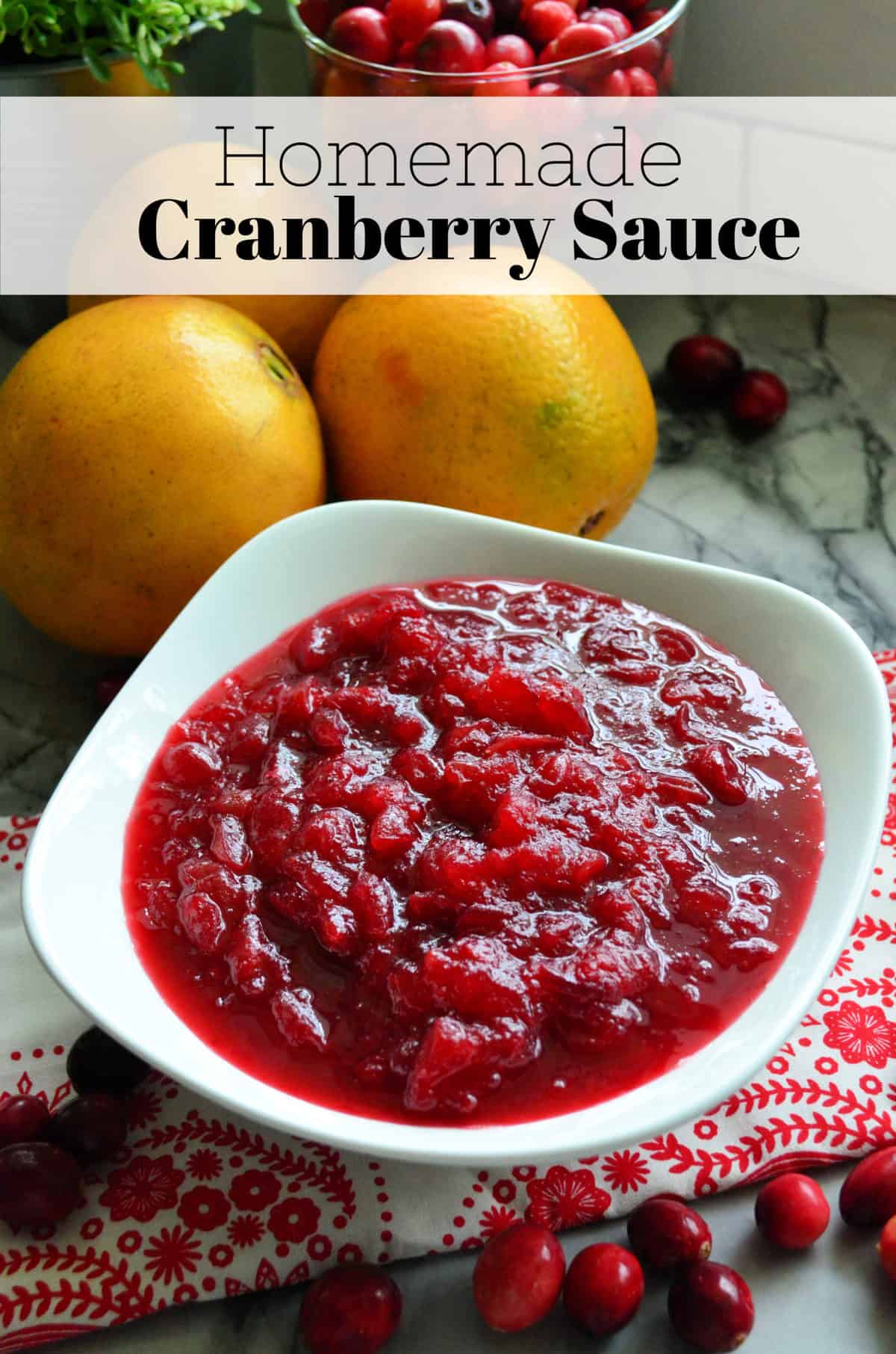 Top view of white bowl with chunky cranberry sauce in front of 3 oranges with title text.