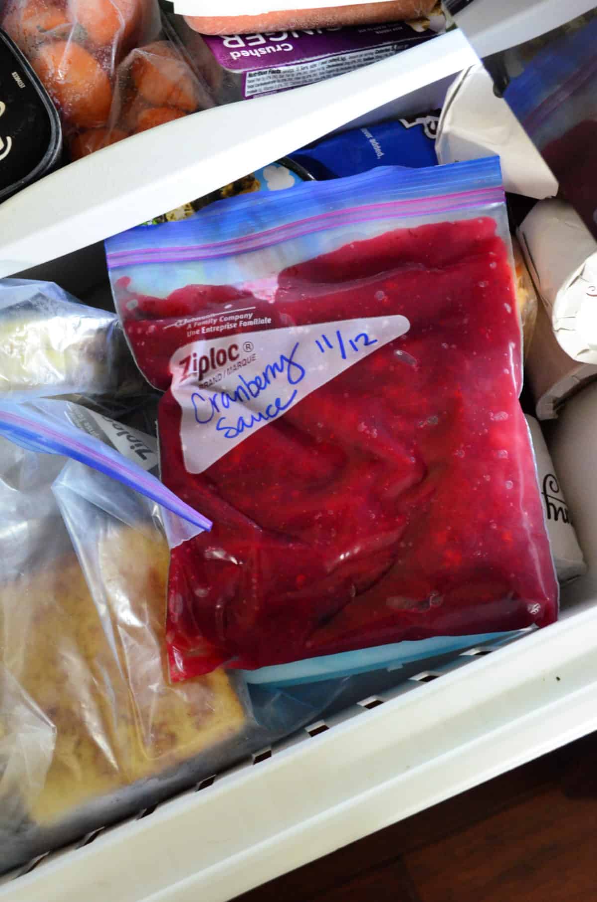 red cranberry sauce packed airtight into ziploc bag with label in freezer.