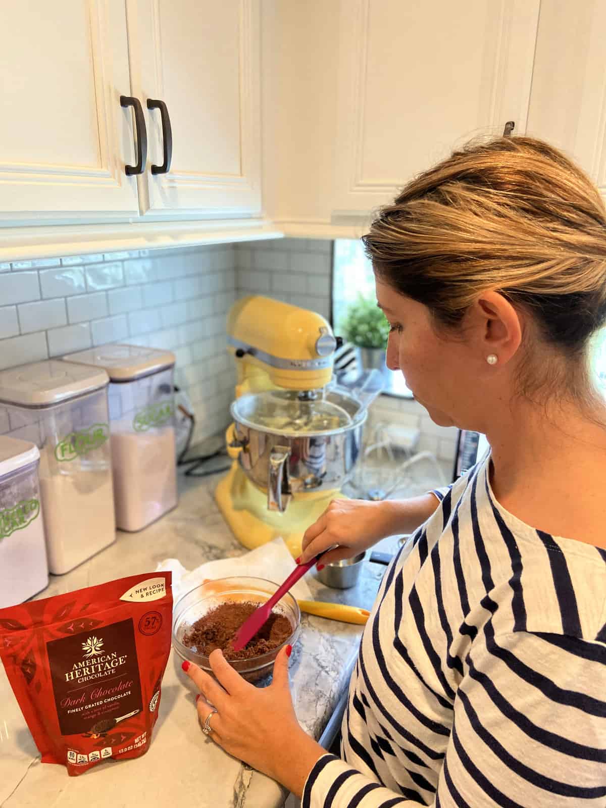 side view of woman stirring american heritage finely grated dark chocolate in glass bowl on counter.