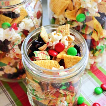 Mason jar filled with chex mix, pretzels, popcorn, m&m's, and raisins.