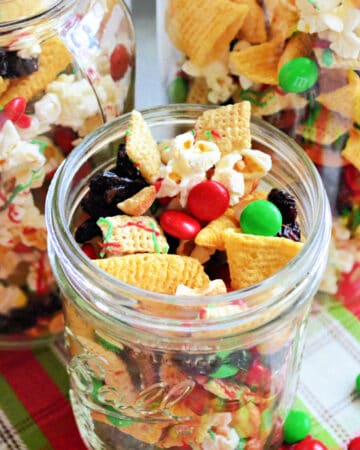 Mason jar filled with chex mix, pretzels, popcorn, m&m's, and raisins.