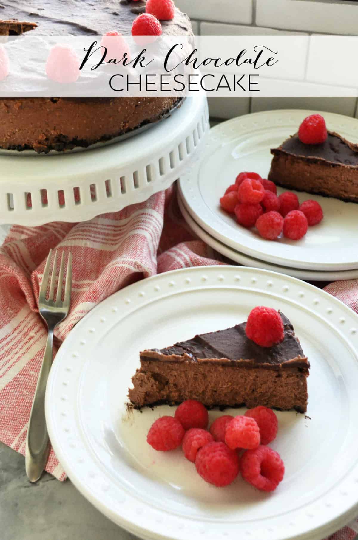 dark chocolate cheesecake decorated with circle of raspberries on cake stand next to two plated slices.