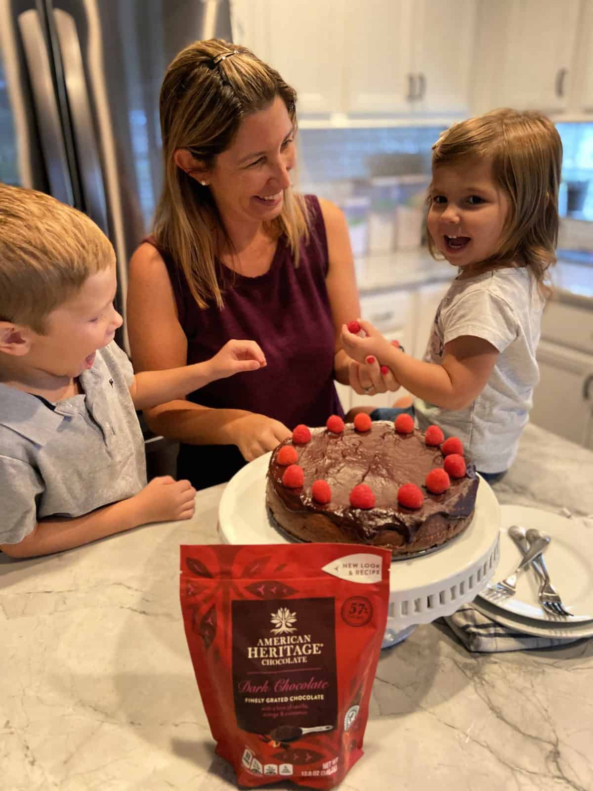 Mother, Daughter, and Son decorating chocolate cheesecake with fresh raspberries.