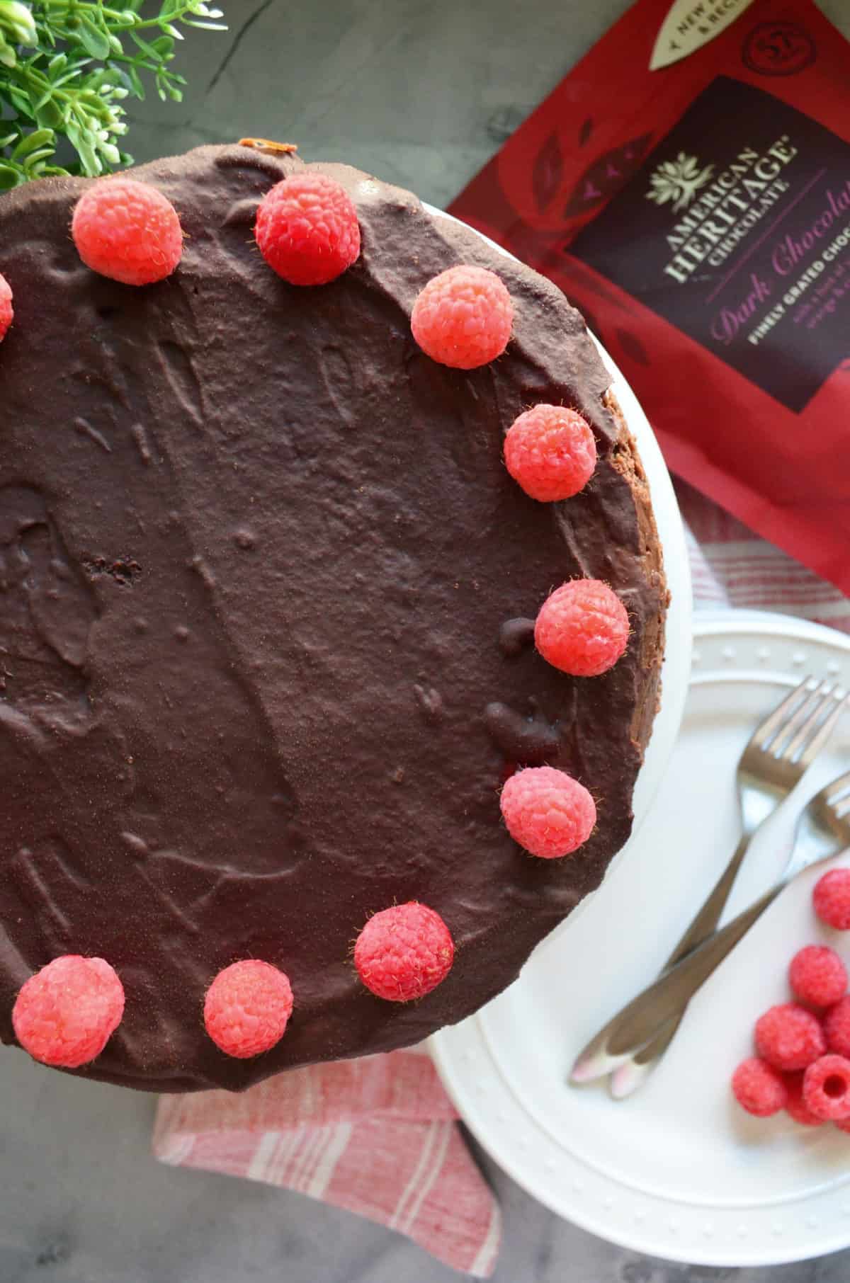 Closeup top view of dark chocolate frosted cake decorated with raspberries as lining.