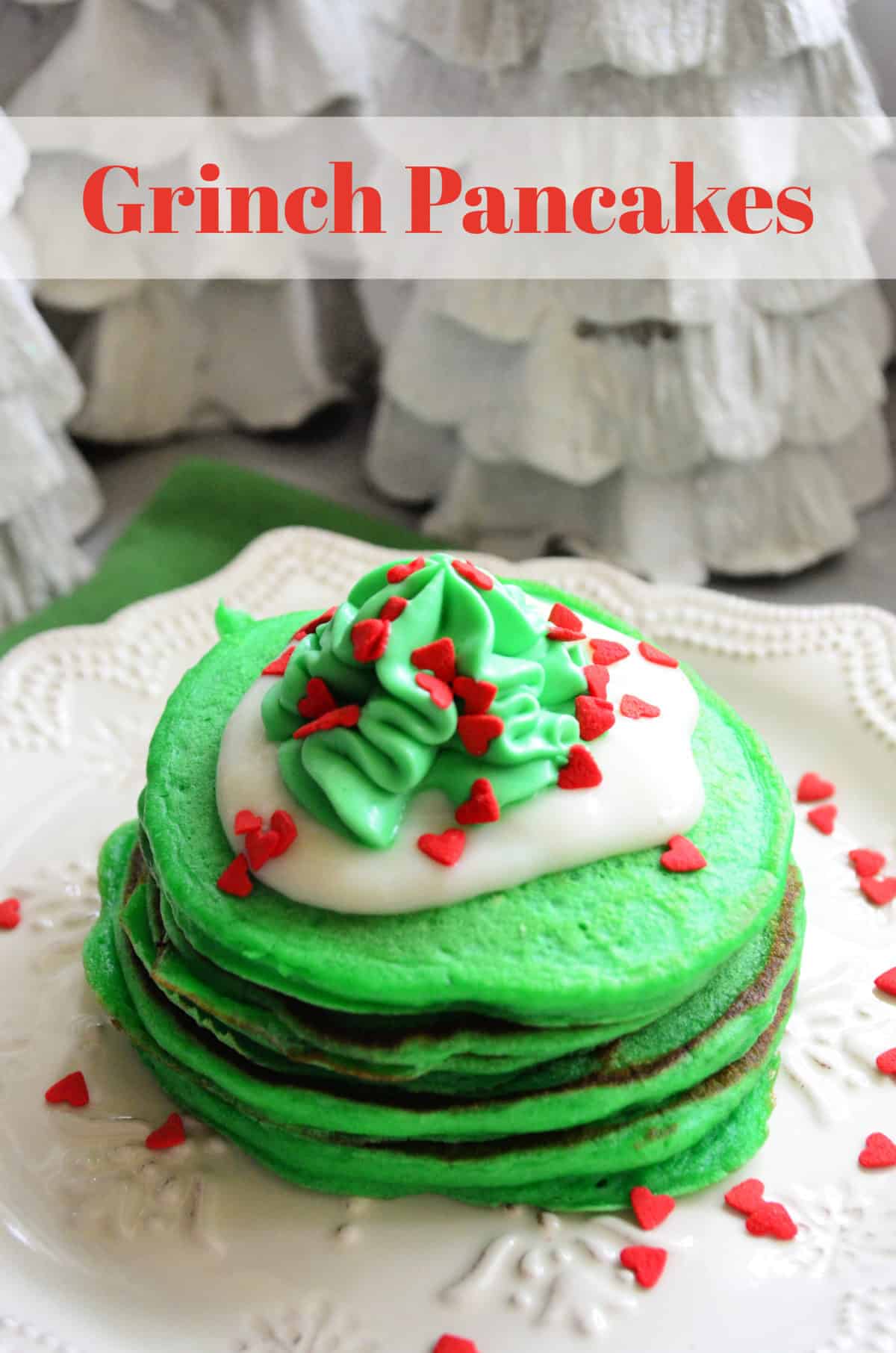 plated green pancakes topped with white frosting, green whipped cream, and red sprinkles and title text.