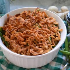 Casserole Dish of Green Bean Casserole Topped with Crispy French Fried Onions on top of tablecloth.