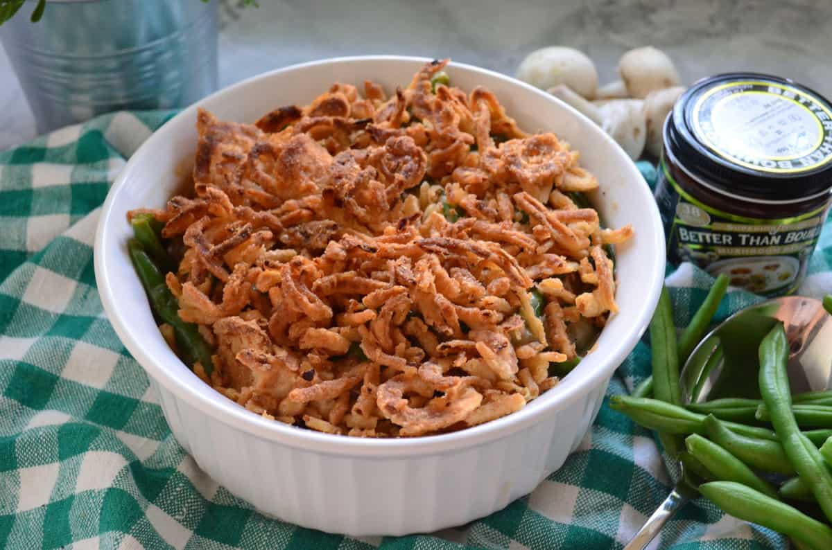 round casserole dish with green bean casserole topped with crispy onions next to green beans.