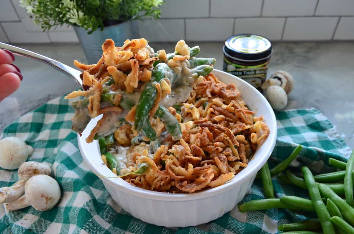 Spoonful of greenbean casserole held over casserole dish full of remnants.