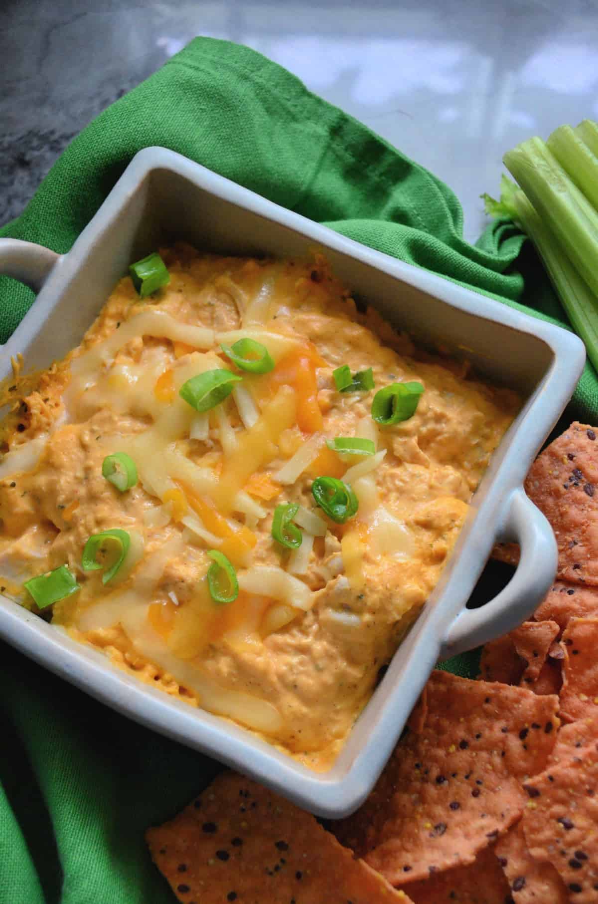 Buffalo Chicken Dip in a square ceramic bowl topped with melted cheese and chives.