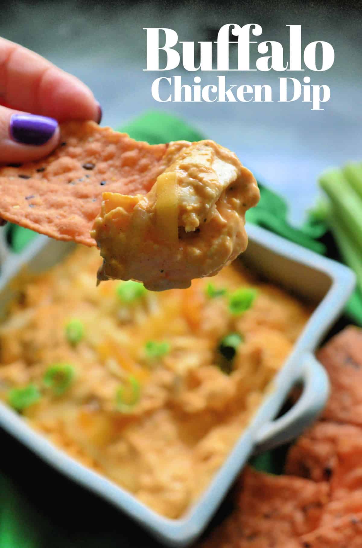 close up of hand holding chip dipped in cheesy buffalo chicken dip with title text.