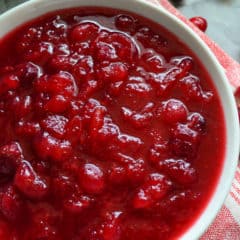Top view of Cranberry Sauce in a white bowl with fresh cranberries around it.