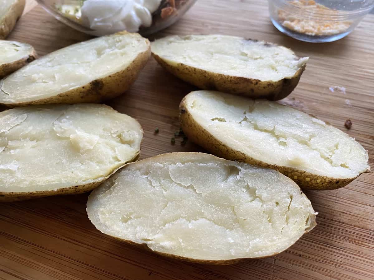 5 potato halves skin side down on wood cutting board.