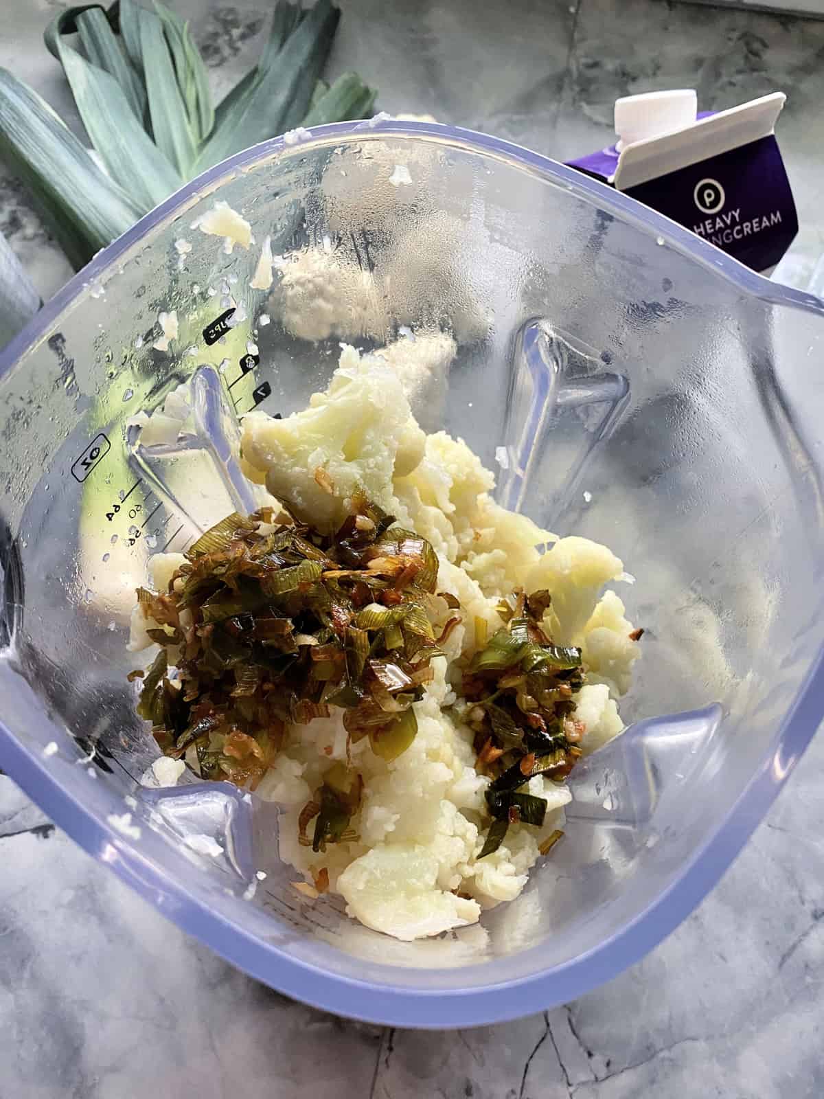 top view of cauliflower, leeks, and spices in blender.
