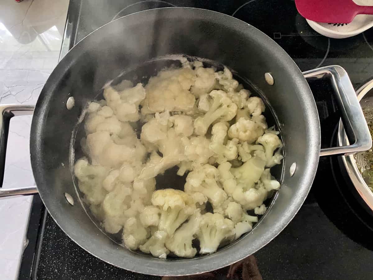 A pot of water with cauliflower boiling in it.