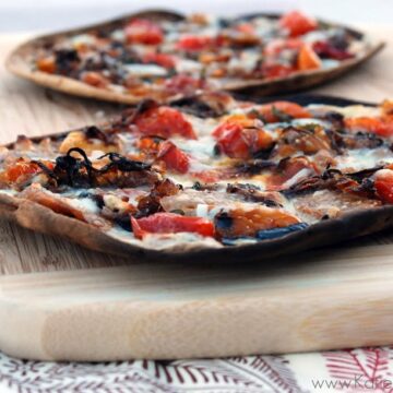 Side view of crisp Grilled Flatbread w/ Hot Italian Sausage, Peppers, & Caramelized Onions.