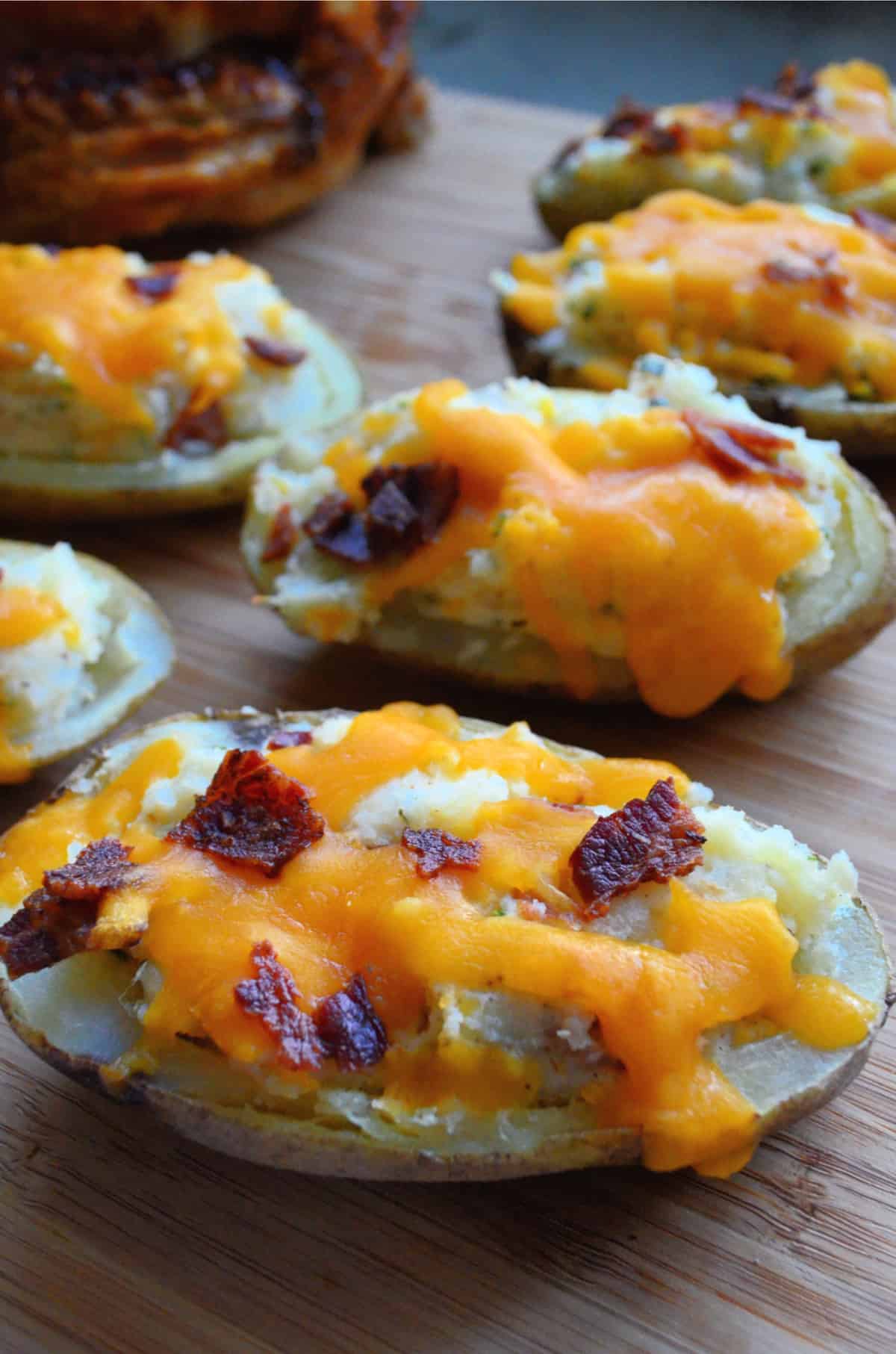 Close up of halved potatoes loaded and topped with melted cheddar and bacon bits.