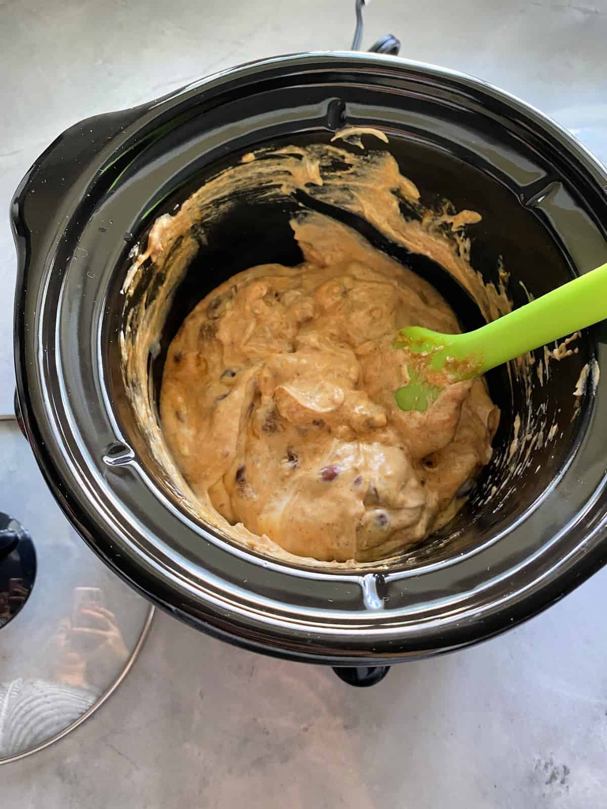 Top view of Chili Cheese Dip being stirred with spatula in a mini Crock Pot.
