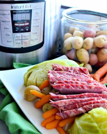 White platter with corned beef, cabbage, carrots, and potatoes with an Instant Pot in the background.