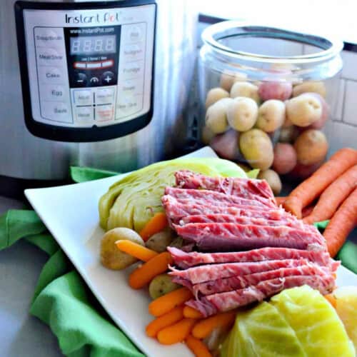 White platter with corned beef, cabbage, carrots, and potatoes with an Instant Pot in the background.