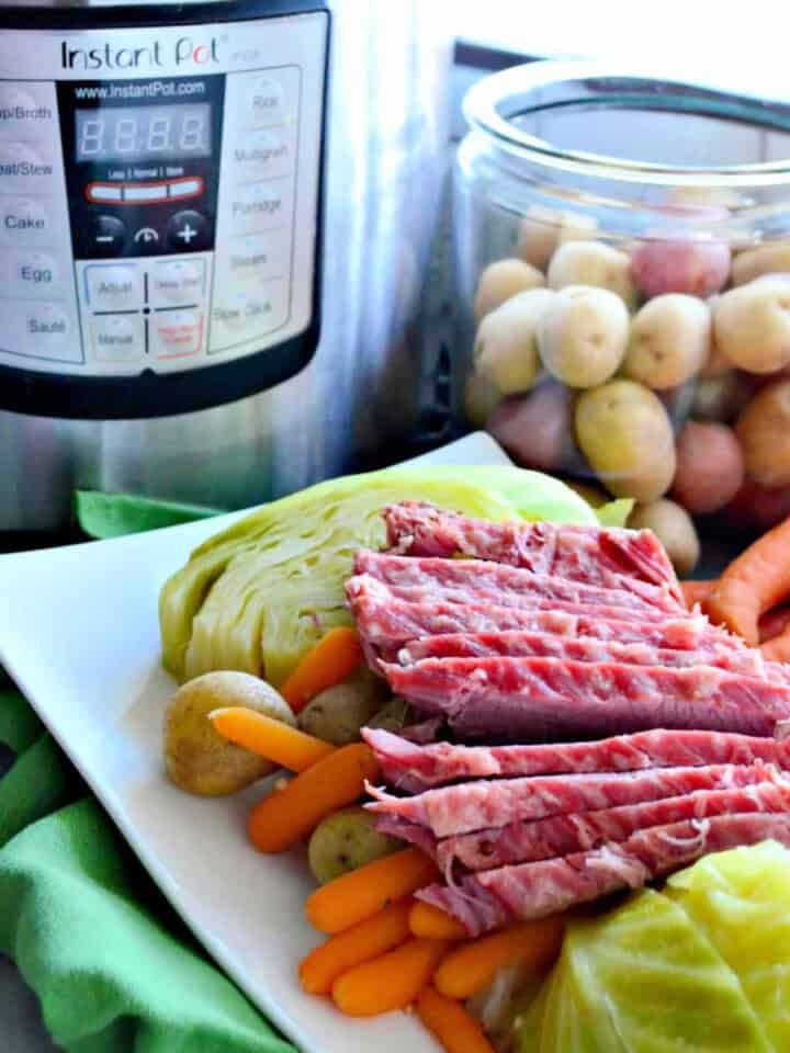White platter with corned beef, cabbage, carrots, and potatoes with an Instant Pot in the background.