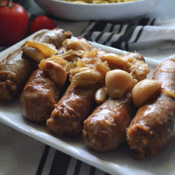 5 Instant Pot Italian Sausage plated and garnished with carmelized garlic and onions.