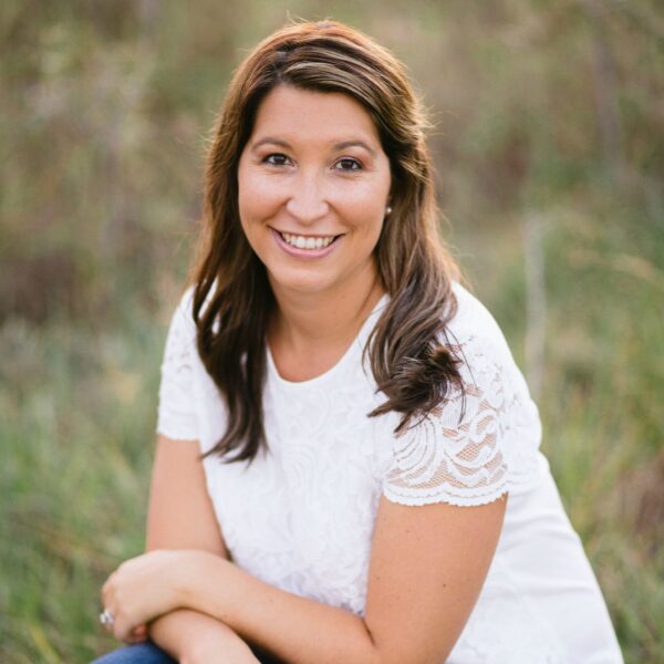 Professional photo of blogger Katie Jasiewicz with long brown hair softly curled with blurred natural background.