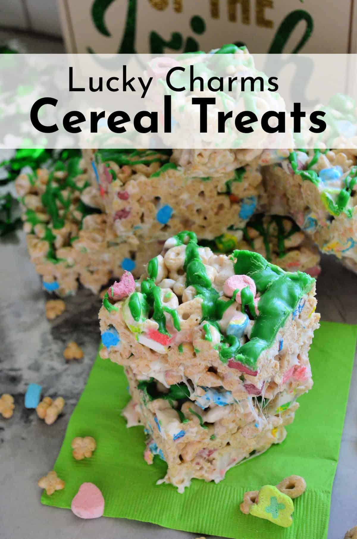 lucky charms cereal treats cut into cubes, drizzled with green chocolate, and stacked with title text.