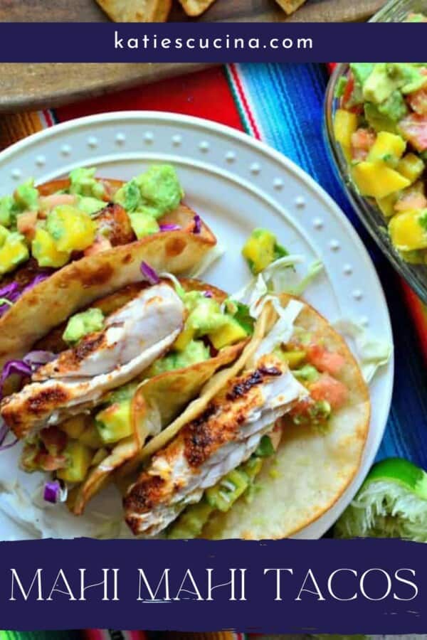 3 soft tacos with fish, avocado, cabbage on a white plate with recipe title text on image for Pinterest.