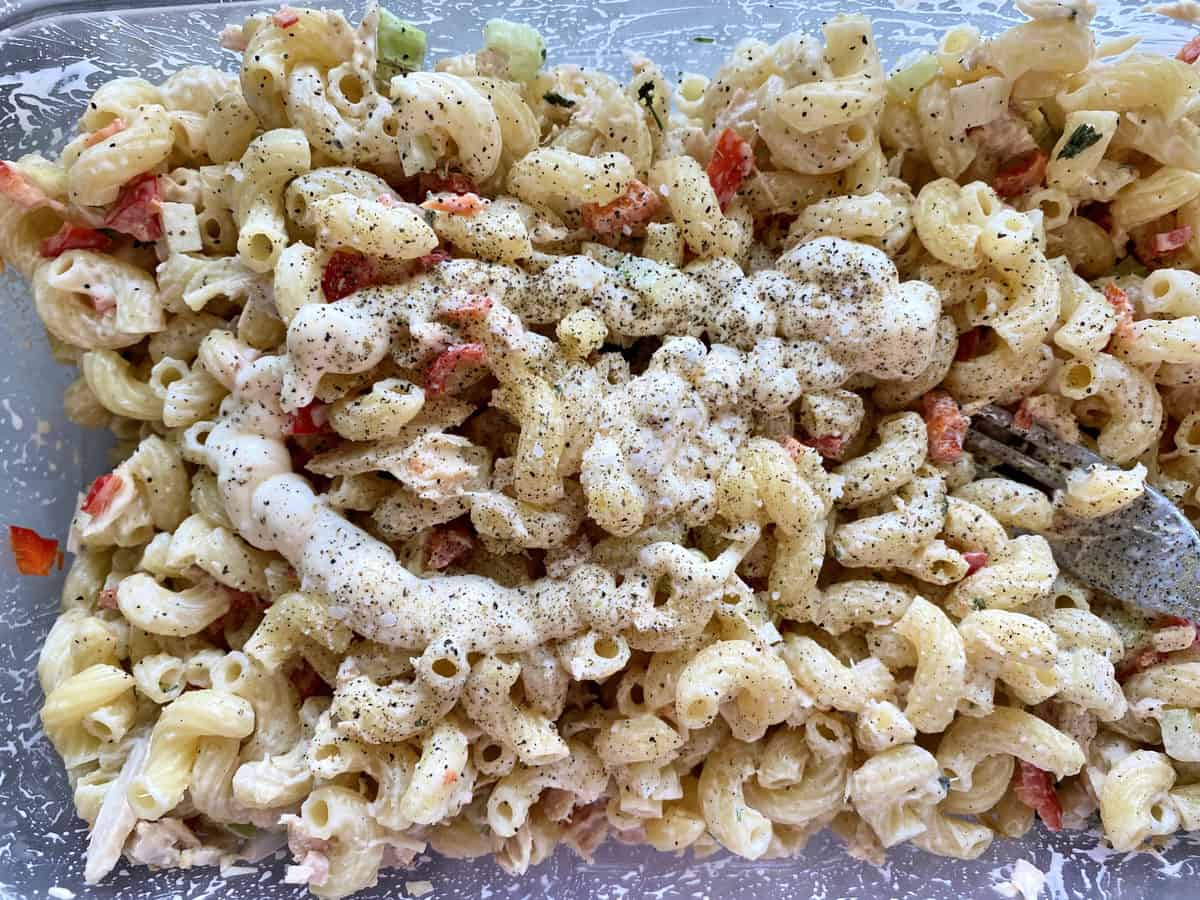 too view of tuna macaroni salad with mayo and pepper on top but not yet mixed in.