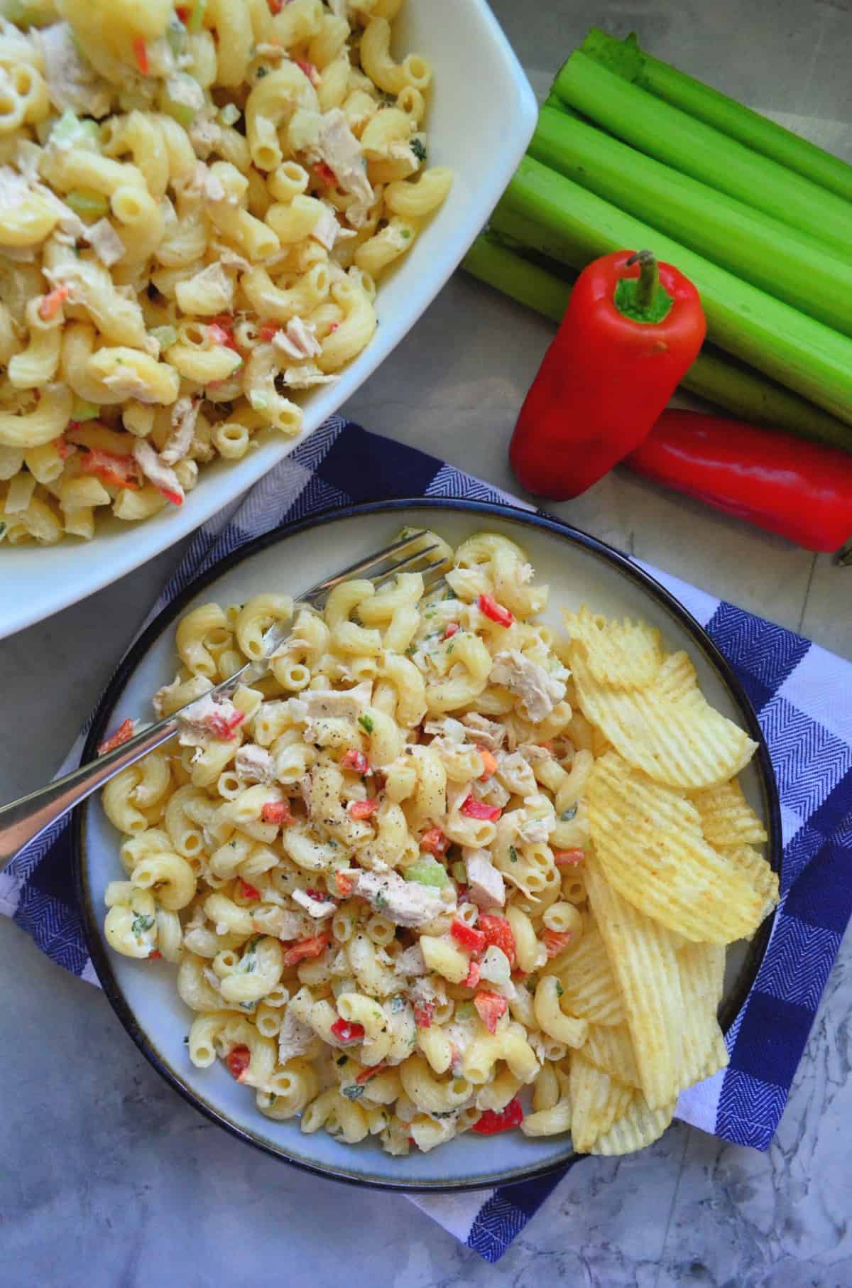 top view plated Macaroni and Tuna Salad with Potato Chips near celery, bell pepper, and remaining salad.