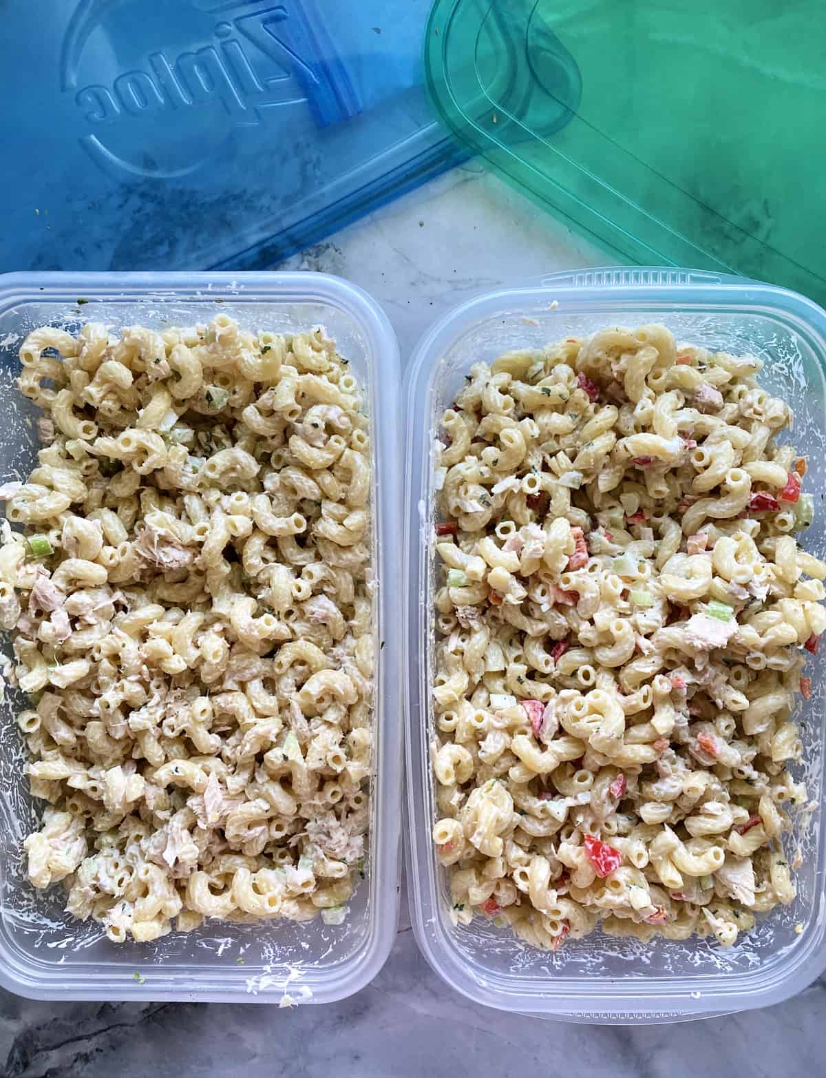 close up top view of Macaroni and Tuna Fish Salad two ways in containers- one without bell pepper.