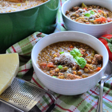 Two bowls of Sausage Lentil Soup with vine-ripe tomatoes in the background.